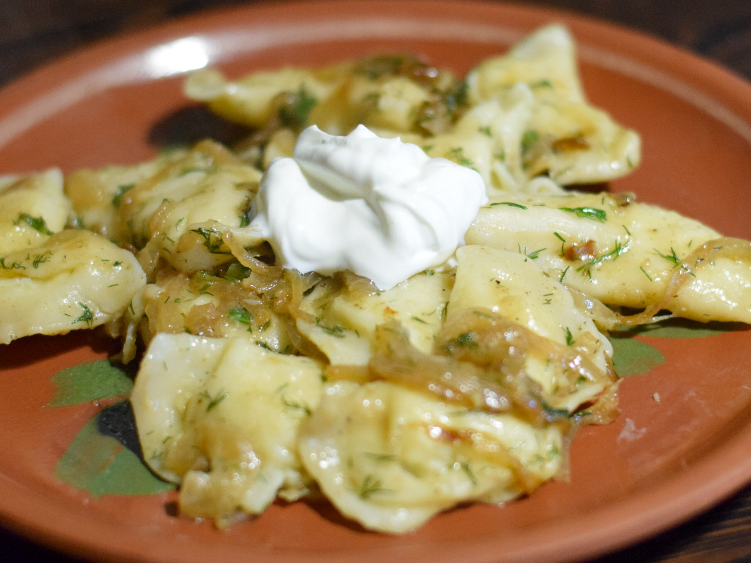 Домашние вареники с картофельной начинкой на тарелке с жареным луком