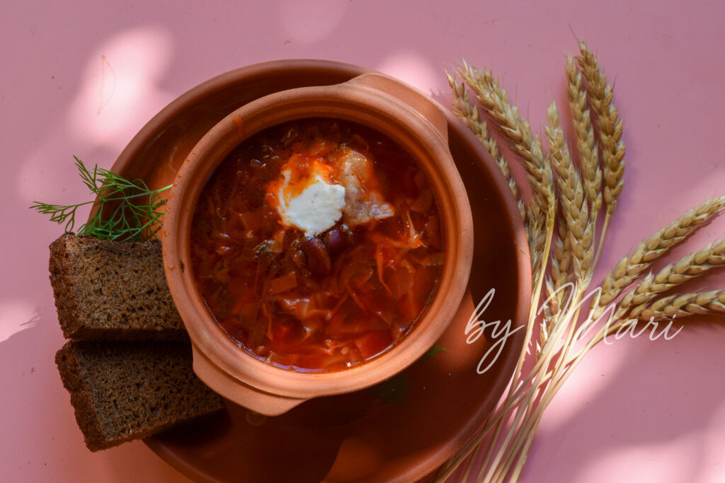 Тарелка борща со сметаной, чесноком и зеленью