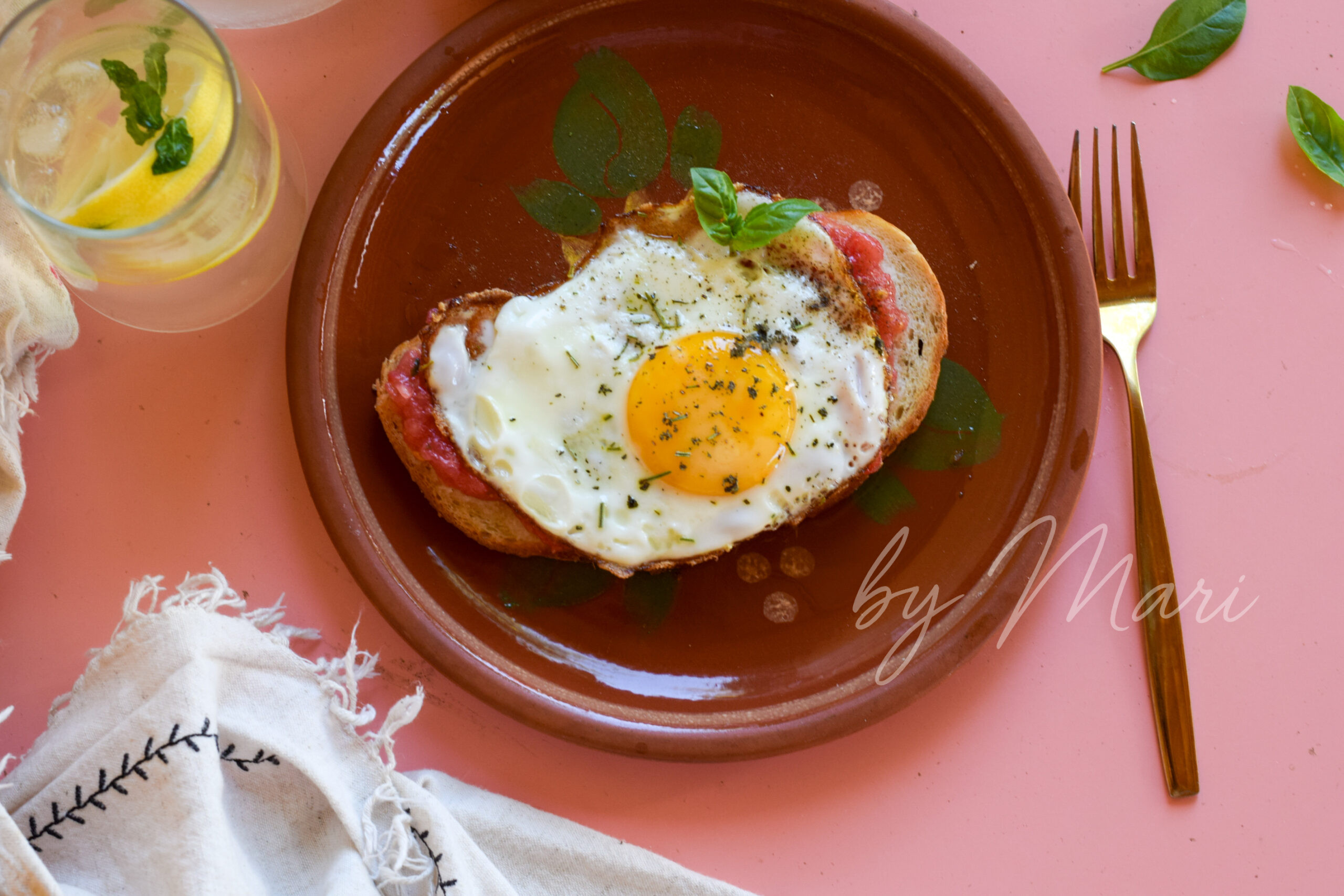 Тост с тёртым томатом и яичницей, украшенный травами, на тарелке